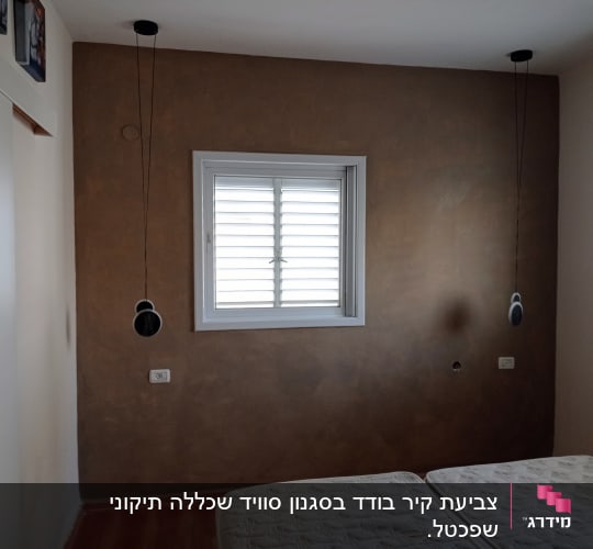 קיר צבוע בגוון חום עם חלון במרכז